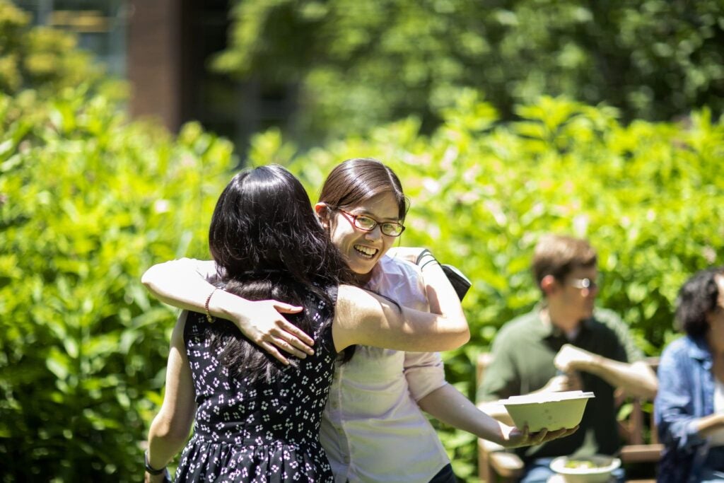 Two CHIBE members hug at a team picnic