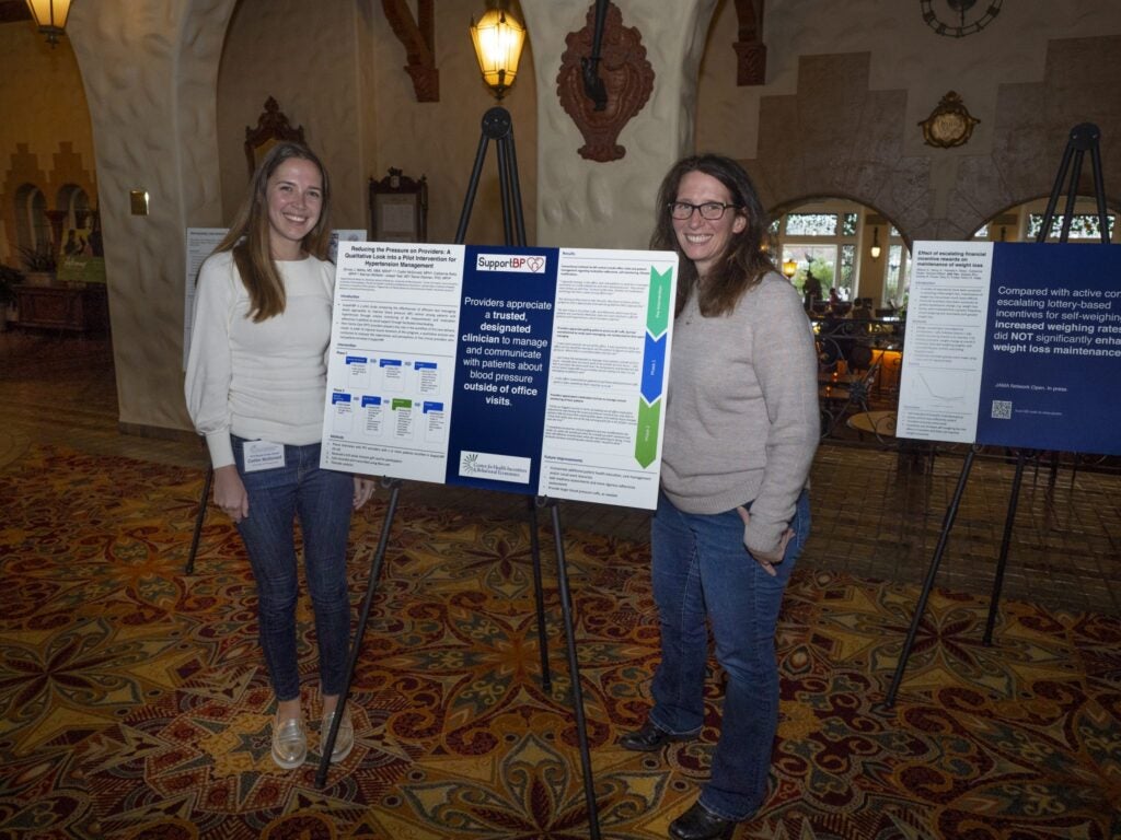 two women with poster presentation on designated physicians to manage blood pressure outside of office visits