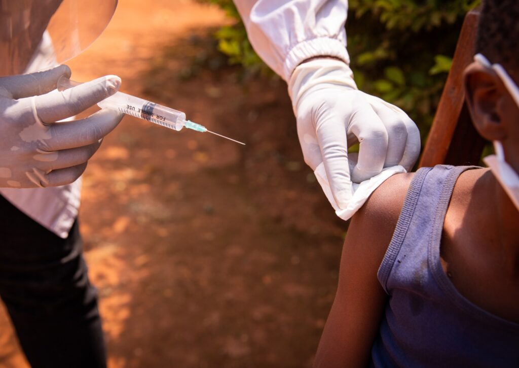 close-up of a doctor's hand with a syringe about to inject a vaccine to a young child in Africa