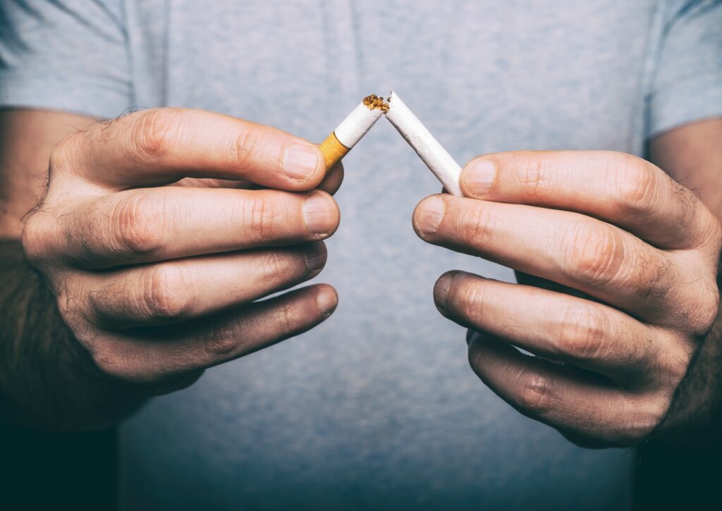 male hands breaking cigarette to demonstrate quitting smoking