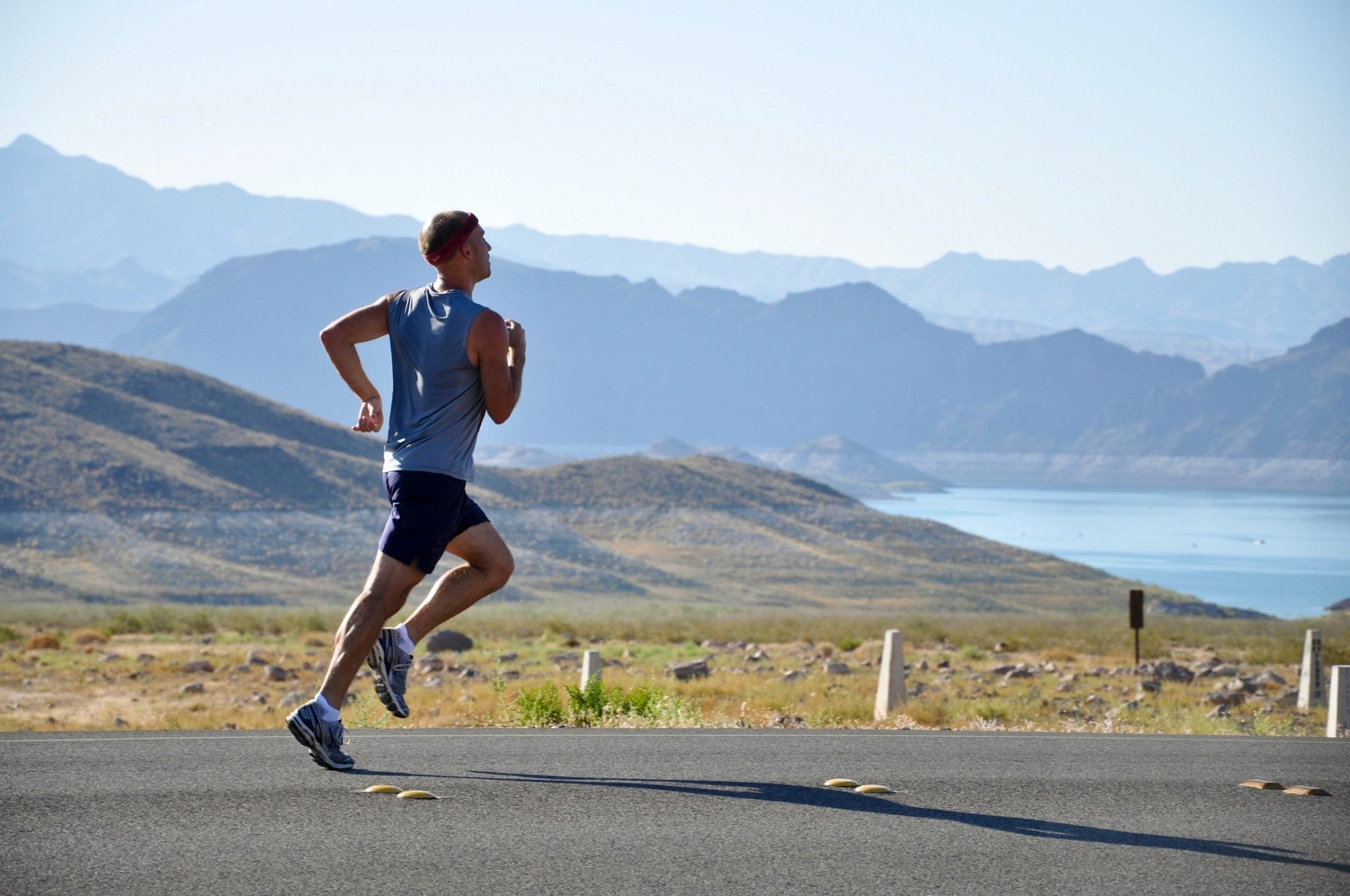 a man running in front of a body of water and mountains