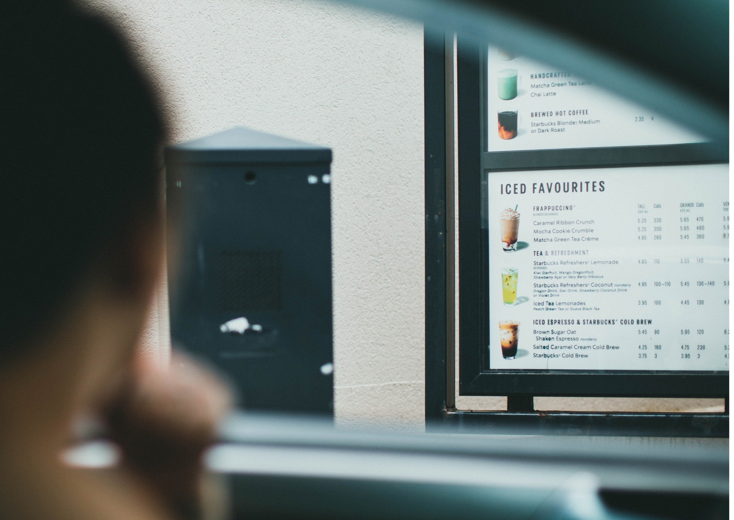 person orders at a drive-through with menu board that needs additional labeling