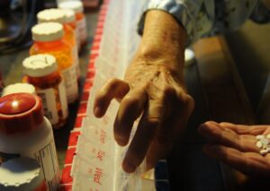 elderly person fills weekly pill containers