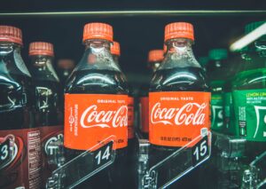 sugary beverage bottles of soda, like coca-cola and sprite, sit in a refrigerated cooler