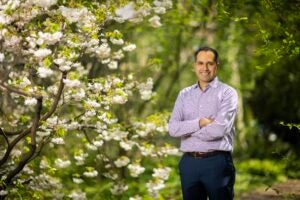 Shivan Mehta standing outside next to flowering tree