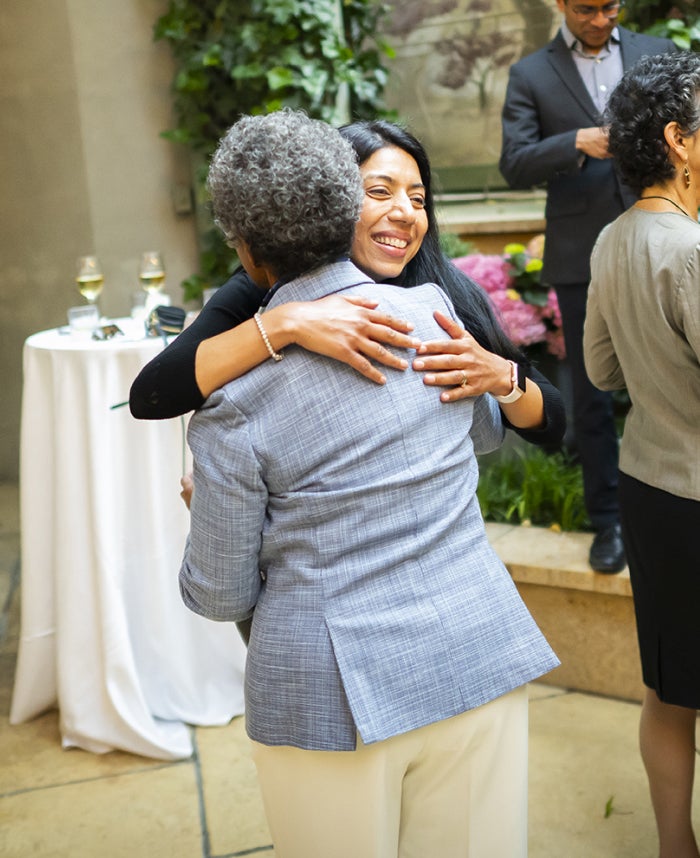 Two women hugging in an outdoor area at a conference