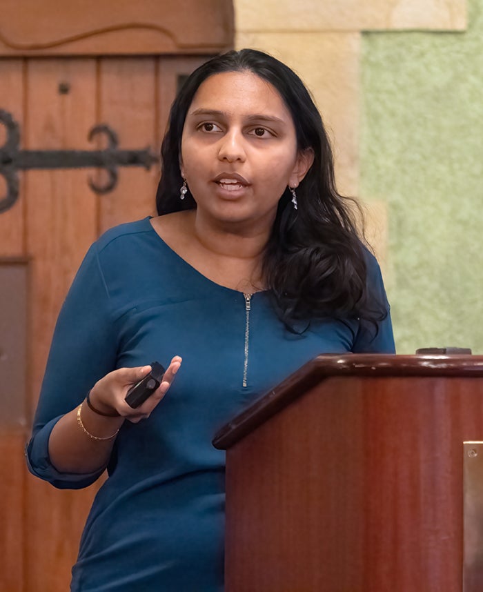 Woman holding a remote clicker giving a talk at a podium