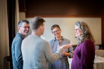 Four symposium attendees chat in a circle during a break.